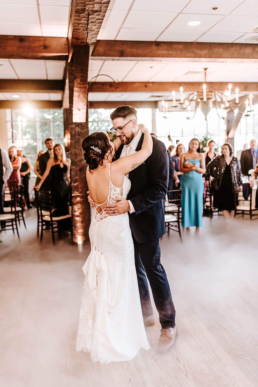 Bride and groom having first dance with smoke surrounding them at the smithville inn, while guests stare with love