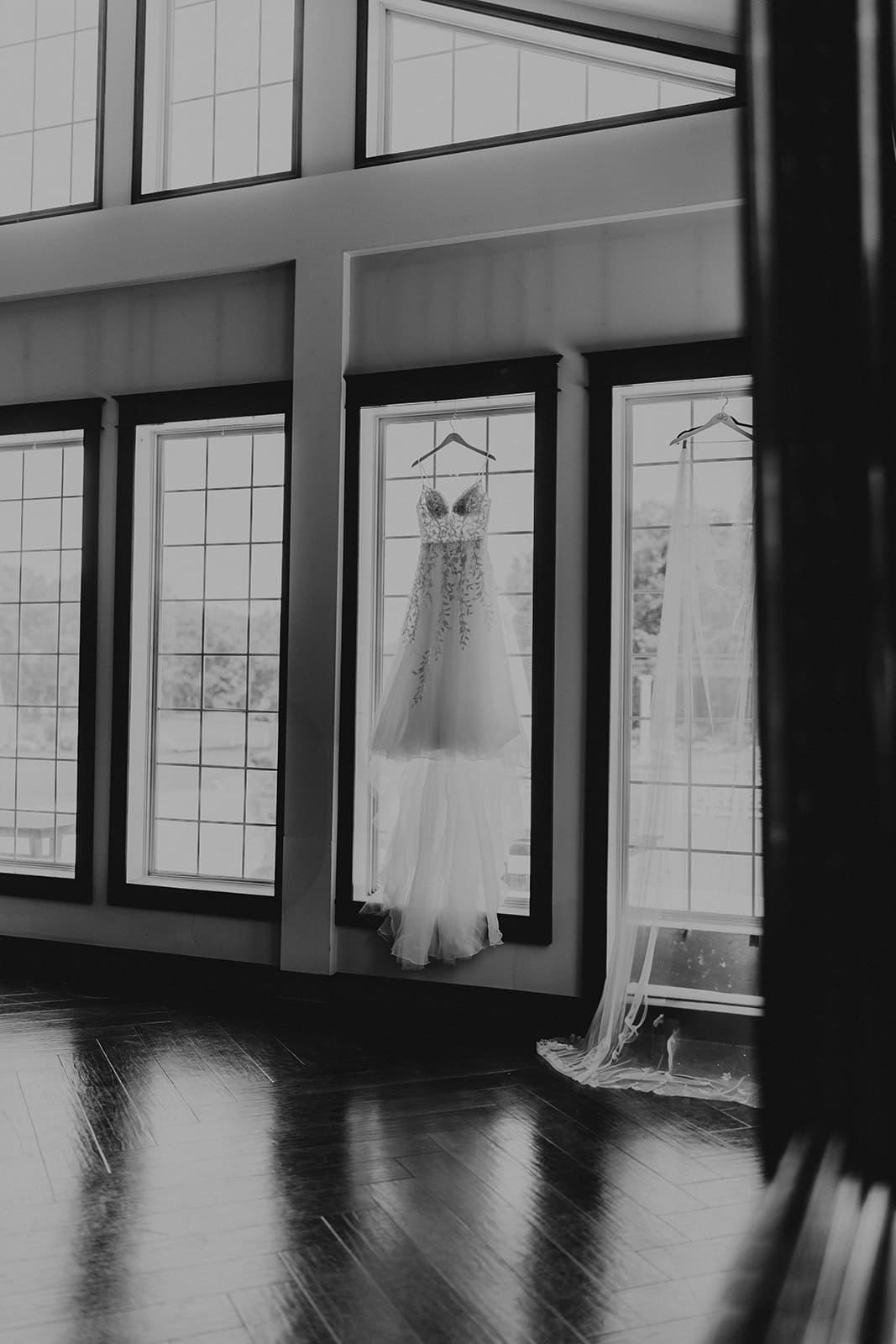 Dress and veil in black and white, hanging from Running Deer Golf Club's ballroom windows.