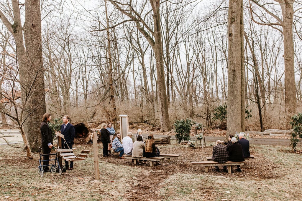 Guests gathering outdoors for an intimate wedding ceremony at London Grove Quaker Meeting House in Kennett Square, PA — a serene woodland setting in Chester County.