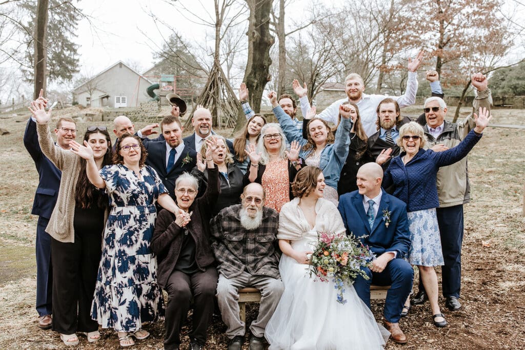 Bride and groom smiling with their loved ones during a joyful group photo at their intimate Chester County wedding near Kennett Square, PA.