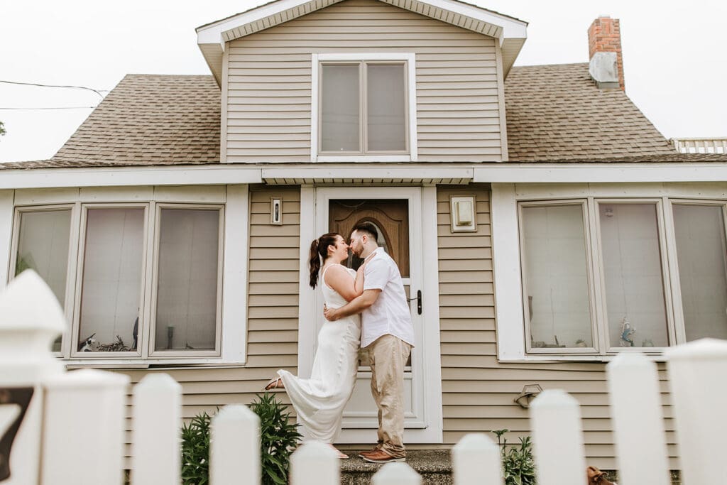 Couple shares a kiss on the front steps of a family beach house in Cape May during their engagement session