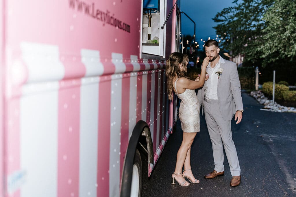 Bride and groom sharing a sweet moment beside the pink Lexylicious ice cream sandwich truck at their Philadelphia wedding.