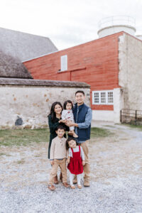 Family posing together during a Christmas mini session at Springton Manor Farm in Glenmoore, PA by a Chester County family photographer.
