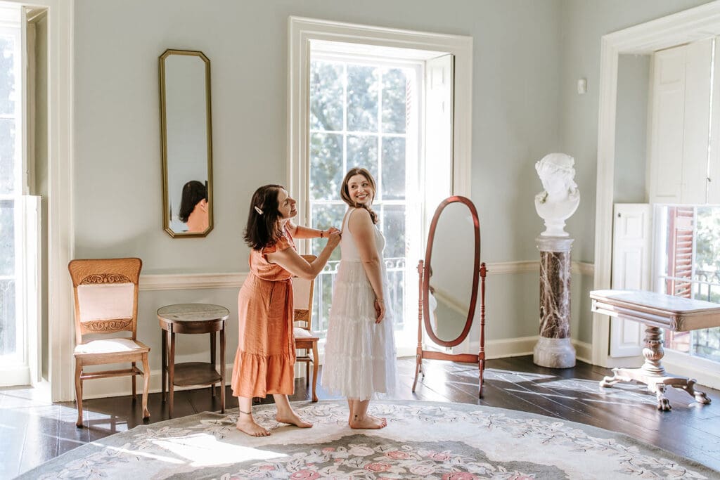 Bride getting dressed with help from her mom inside Highlands Mansion, bridal suite portraits at an intimate Pennsylvania wedding.