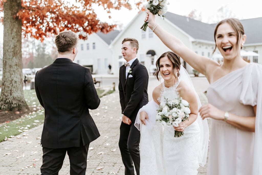 Bride laughing with her wedding party outside Running Deer Golf Club during portraits.