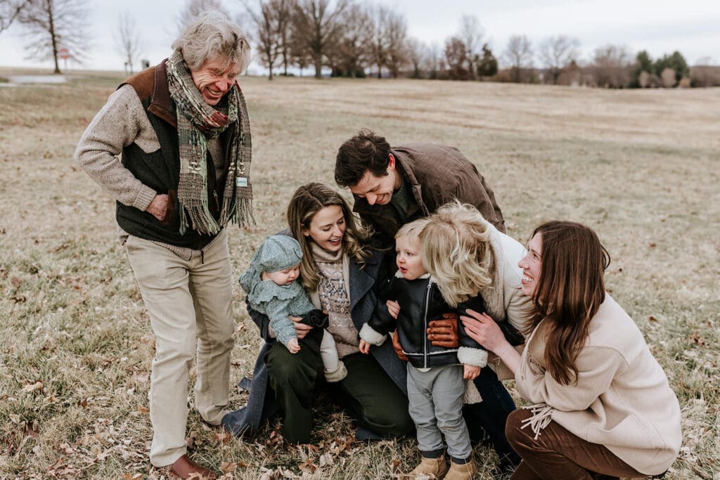 Three-generation family gathered together during a winter extended family photography session at Valley Forge Historic National Park, with grandparents, parents, and young children sharing a candid moment outdoors.