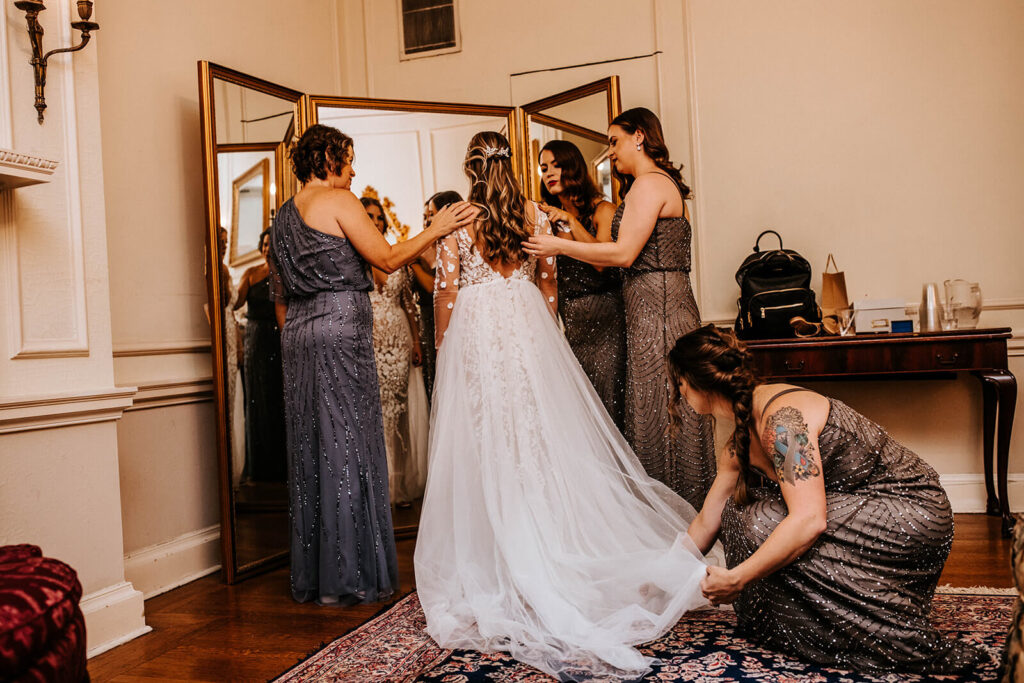 bridemaids help bride get ready at Stotesbury Mansion