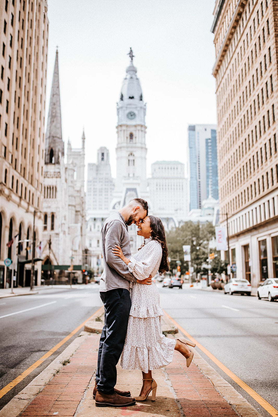 Couple embracing in front of Philadelphia City Hall during an engagement session in Center City Philadelphia