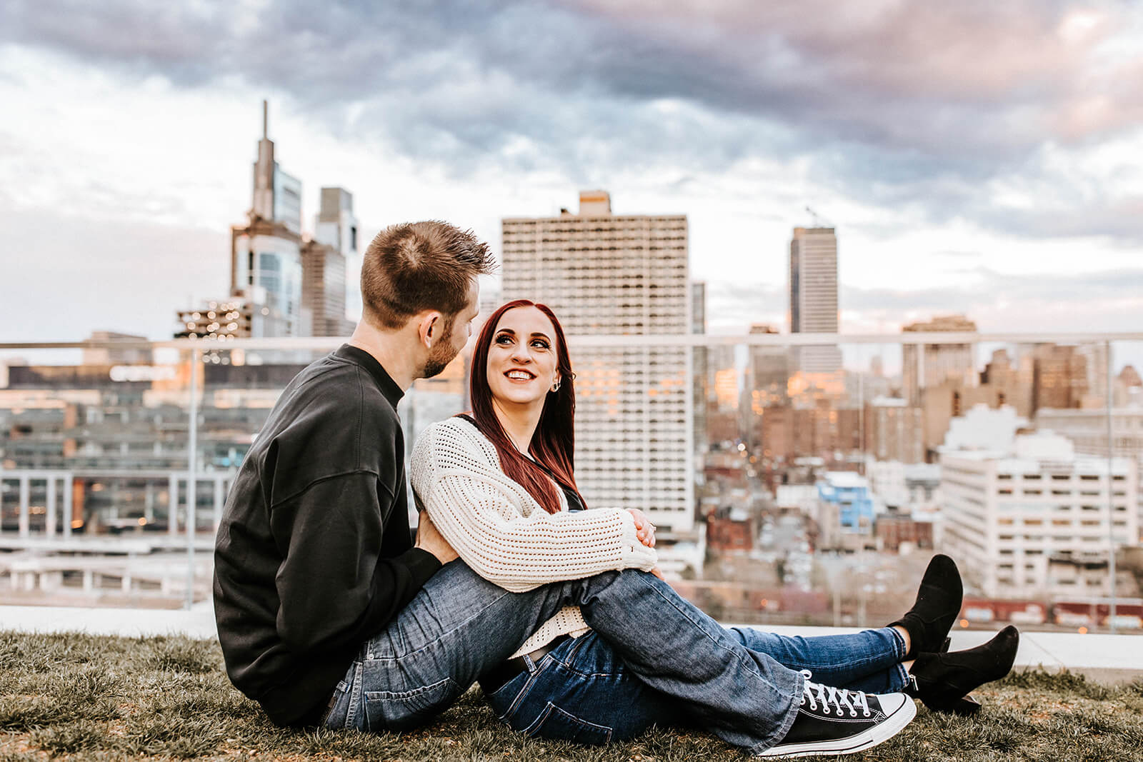 couple sitting together holding a personalized sign during their Philadelphia engagement session.