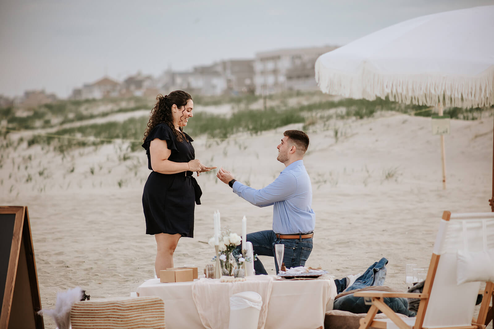 Romantic beach proposal moment as groom-to-be kneels and proposes during luxury picnic setup at Bradley Beach.