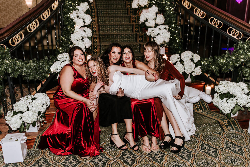 Bride posing with bridesmaids in front of the grand staircase at Collingswood Grand Ballroom